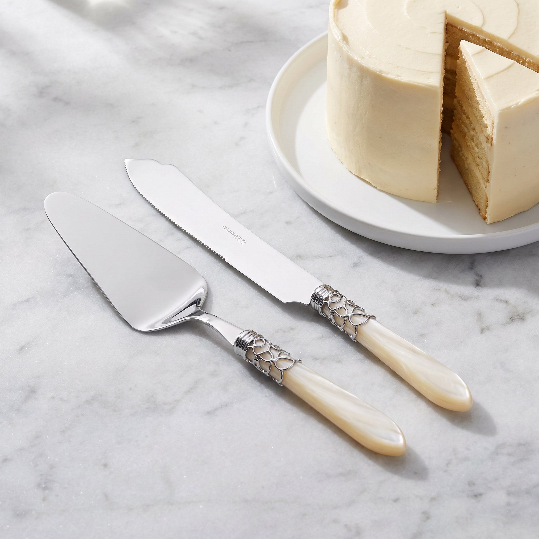 Two-piece cake serving set beside an ivory layer cake on grey marble