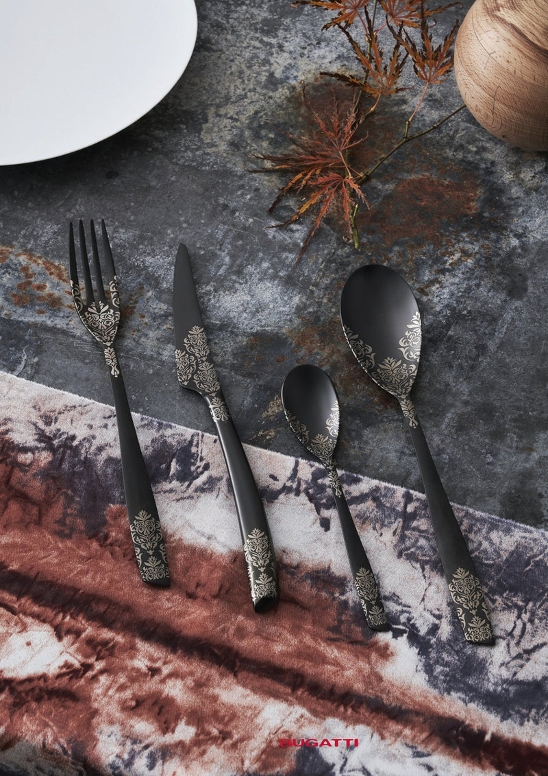 Black and gold flatware on stone