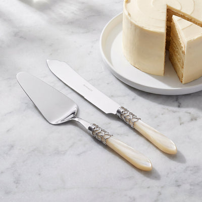 Two-piece cake serving set beside an ivory layer cake on grey marble