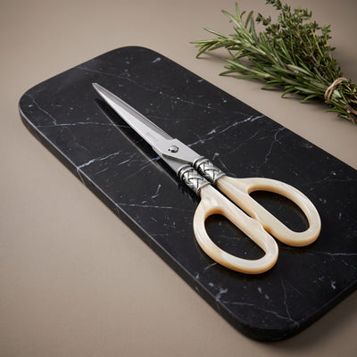 Casa Bugatti kitchen shears with pearlescent ivory handles on a black Marquina marble board