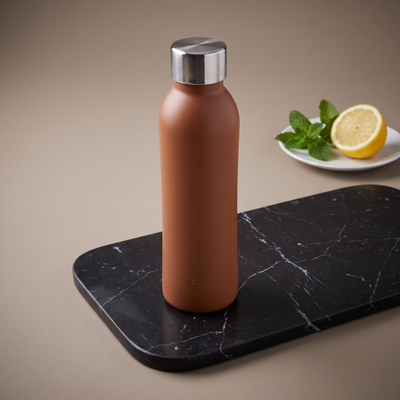 Casa Bugatti B Bottle in terracotta with steel cap on black marble, lemon and mint